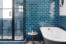 23 bright teal tiles on the wall are accented with white grout, and a hex tile floor adds interest