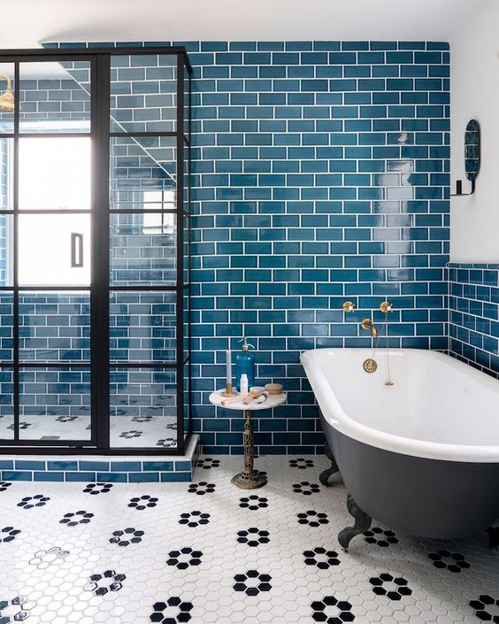 bright teal tiles on the wall are accented with white grout, and a hex tile floor adds interest