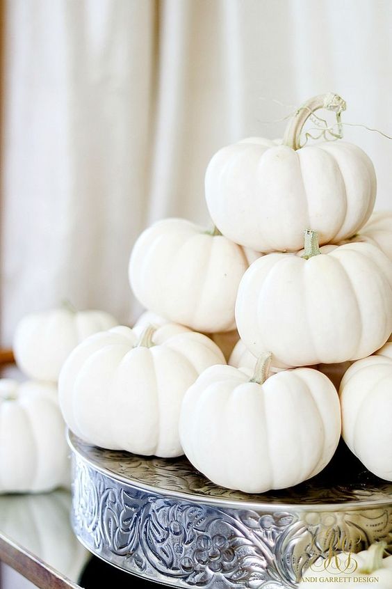 a glam fall arrangement of a vintage metal holder and a stack of white pumpkins