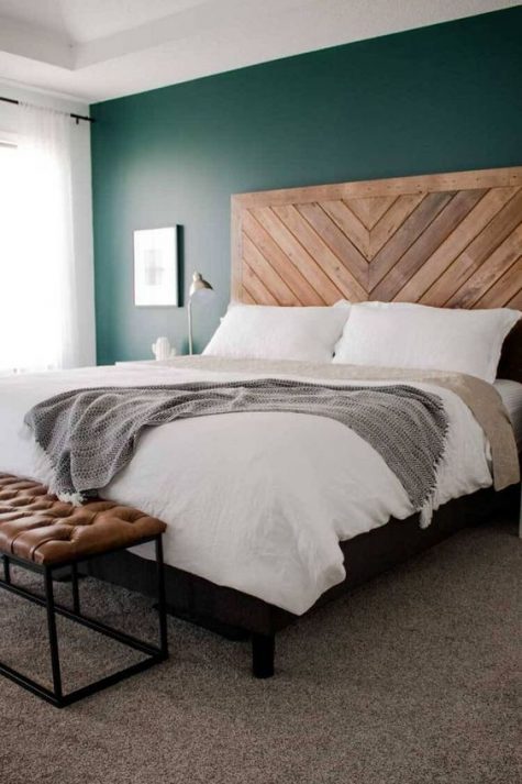 a wooden headboard done in a chevron pattern and a leather bench add texture to the bedroom