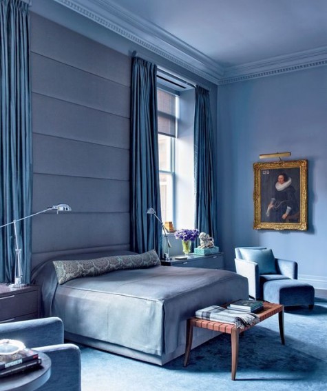 an oversized blue upholstered headboard coming up to the ceiling softens the space visually and makes it more modern