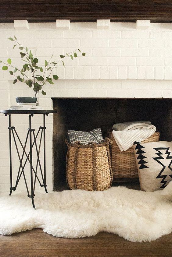 style your non-working fireplace with baskets with blankets and throws and a faux fur rug