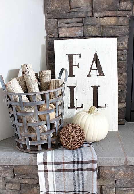 a metal basket with branches, a plaid blanket, a vine ball, a white pumpkin and a sign