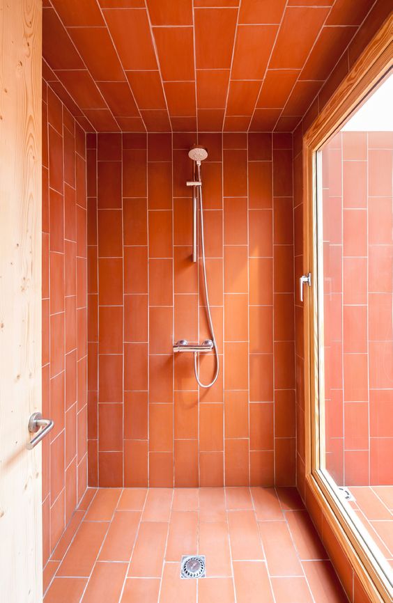 a shower space accented with brigth coral tiles to make it stand out in the bathroom