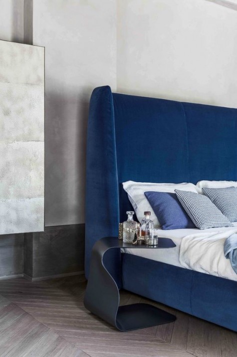 an ultra modern electric blue wingback headboard accented with a catchy curved nightstand