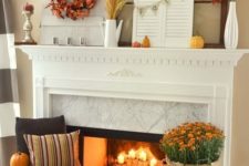 27 a fall fireplace with candles, bright blooms, pumpkins, pinecones, leaves and a candle lantern