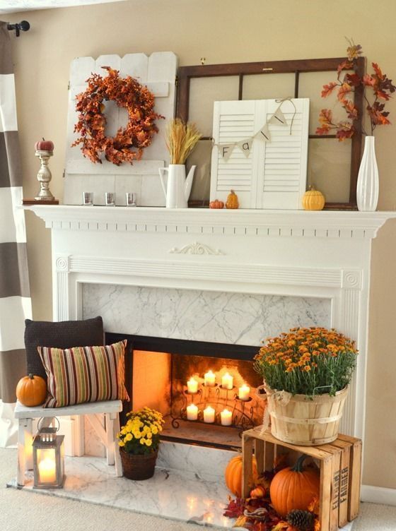 a fall fireplace with candles, bright blooms, pumpkins, pinecones, leaves and a candle lantern