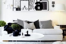 a Nordic living room with a gallery wall on a ledge, a white sofa, leather ottomans and a pack of striped pillows