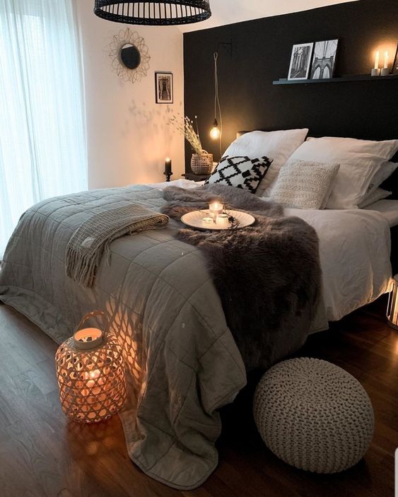 a Scandinavian bedroom with a black accent wall, a bed with neutral bedding, nightstands, lamps, lights and lanterns