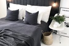 a Scandinavian bedroom with a black bed with an extended headboard, black and white bedding, a chair and a basket