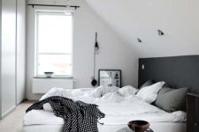a black and white bedroom with a black accent, a bed with monochromatic bedding, a hidden wardrobe and some lamps