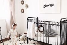 a black and white nursery with a printed rug, a black bed, a bead chandelier and a simple artwork