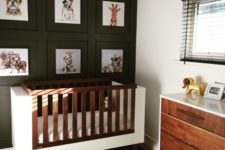a black and white space with a black statement wall, a modern crib and dresser, black shades and a buffalo check rug