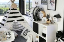 a bold adventuruous nursery with a striped teepee, a dresser, a gallery wall and a play rug on the floor