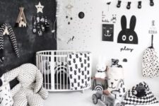 a catchy and bold nurseyr with a black wall, some prints, a gallery wall of artworks and garlands and lot sof toys