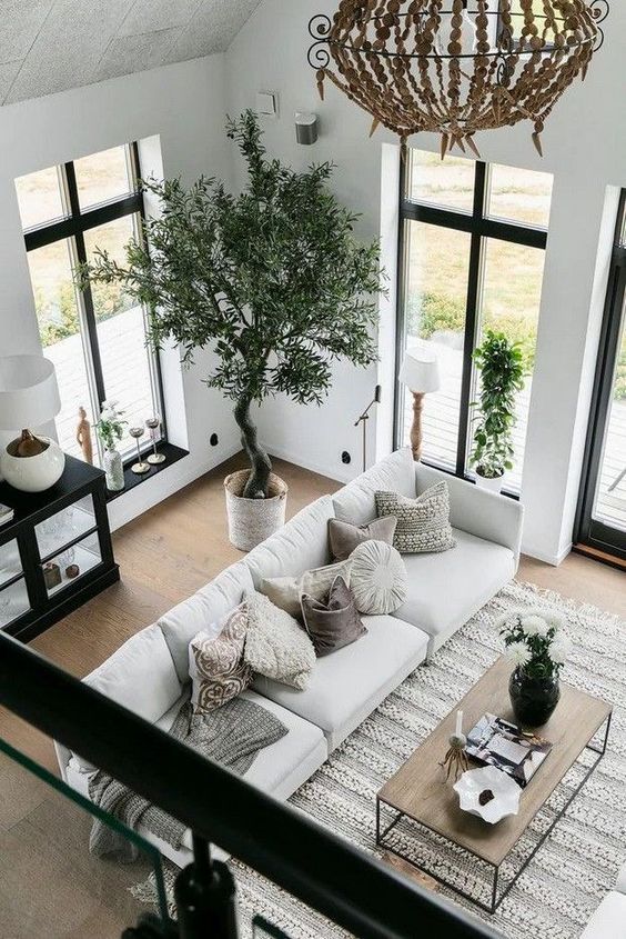 a chic black and white living room diluted with some natural wood and a crochet rug plus greenery for a welcoming feel