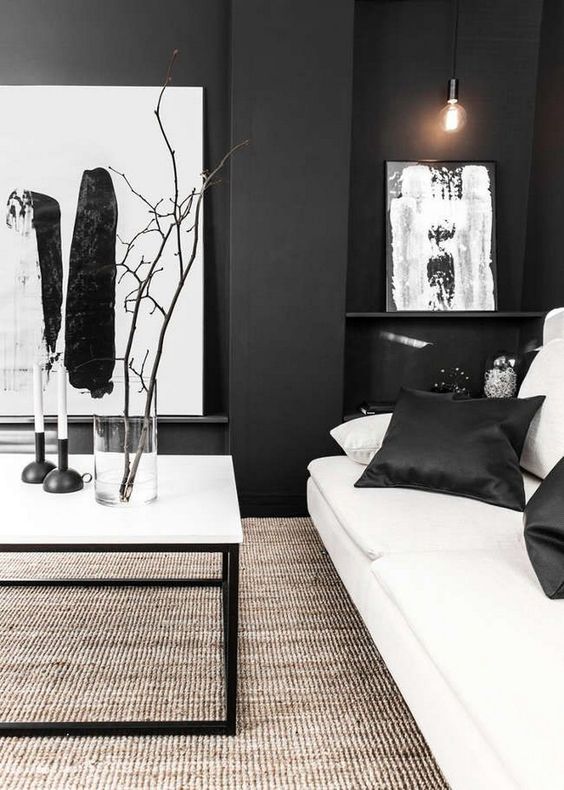 a chic black and white living room with graphic artworks, a white sofa, a coffee table and a textural rug