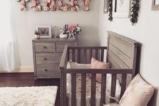 a chic farmhouse meets vintage and boho nursery with reclaimed wooden furniture, a floral name, fluffy rugs and artworks