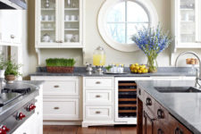 a chic rustic kitchen with white and stained furniture, a porthole window and lots of greenery and blooms