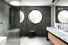 a contemporary bathroom with concrete tiles, a marble vanity, a round pivot window for a modern feel