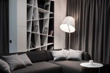 a contemporary black and white living room with a built-in geometric shelf, a sectional sofa and a black ottoman