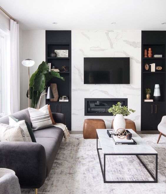 A cozy Scandinavian living room with a marble wall, a built in fireplace and chic furniture plus potted greenery
