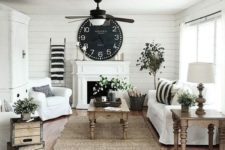 a cozy farmhouse living room in black and white is warmed up with natural wooden furniture and potted greenery