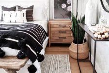 a lovely boho bedroom with a white bed and monochromatic bedding, a console with decor, some plants and decor