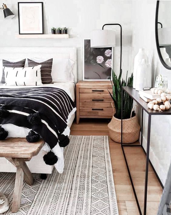 a lovely boho bedroom with a white bed and monochromatic bedding, a console with decor, some plants and decor