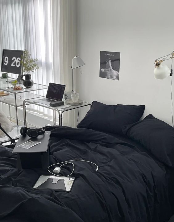 a minimal bedroom with a black bed and bedding, nightstands and lamps and some decor on the tables