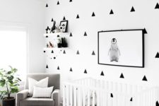 a modern black and white nursery with a patterned wall, a printed rug, a white crib and a penguin artwork
