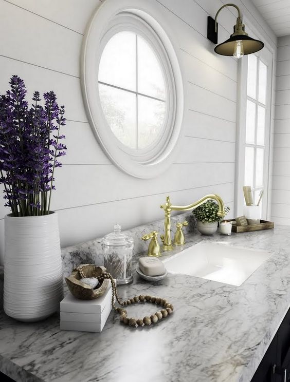 a modern farmhouse kitchen with a marble countertop and a porthole window plus a usual one next to it
