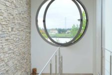 a modern porthole window in the staircase space is a cool way to add light and create an illusion of more space