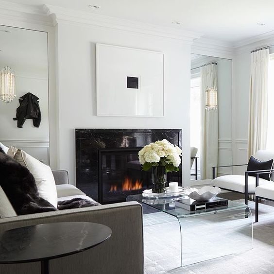 a refined contemporary living room with a sleek black fireplace, a sheer acrylic table and some black touches for drama