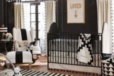 a refined nursery with lots of prints, a crystal chandelier, a black and white crib and gorgeous furniture