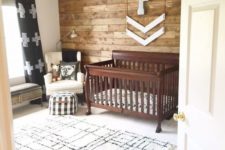 a rustic nursery with a printed rug, a stained crib, a reclaimed wall and some touches of prints