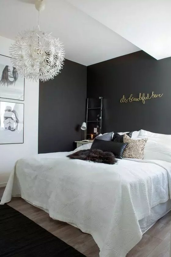 a small and lovely bedroom with black accent walls, a bed with white bedding and black pillows, a gallery wall and gold calligraphy