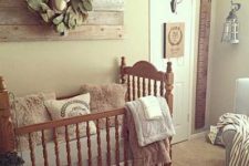 a small vintage farmhouse nursery with a reclaimed wood artwork, a vintage crib, cozy rugs and furniture