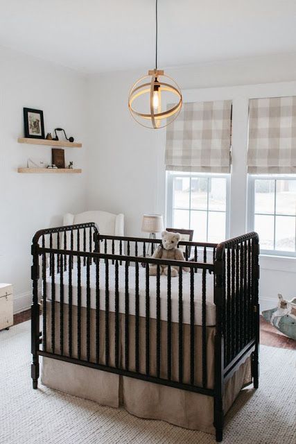 a small yet cozy nursery with plaid Roman shades, a vintage black crib, a sphere pendant lamp and floating shelves