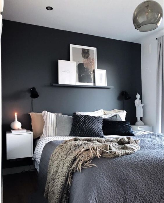 a stylish bedroom with a black accent wall, a bed with monochromatic bedding, floating nightstands and wall lamps