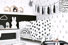 a stylish black and white nursery with monochromatic furniture, a tassel garland, a white crib and lots of prints