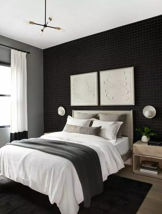 a welcoming bedroom with a black accent wall, a grey bed with neutral bedding, stained nightstands and a black rug