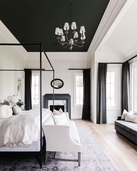 an exquisite bedroom with paneling, a black ceiling and a fireplace with a black mantel, a framed and a white loveseat