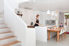 02 The kitchen is done with sleek white cabinets, catchy pendant lamps and some wooden furniture