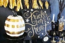 02 a black and gold dessert table with black and gold tassel garland, a striped pumpkin, glitter and some spider glasses