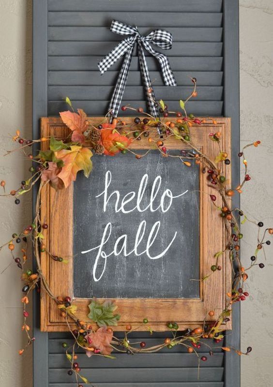 a chalkboard sign decorated with berries and greneery and accented with a plaid ribbon and bow for the fall