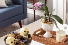 02 a chic Halloween coffee table with a potted bloom, a bowl with spiders, skulls and pinecones and some bones in a shell