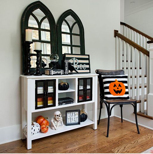 a bright Halloween entryway with skeletons, pumpkins, signs and a pumpkin pillow is easy to realize