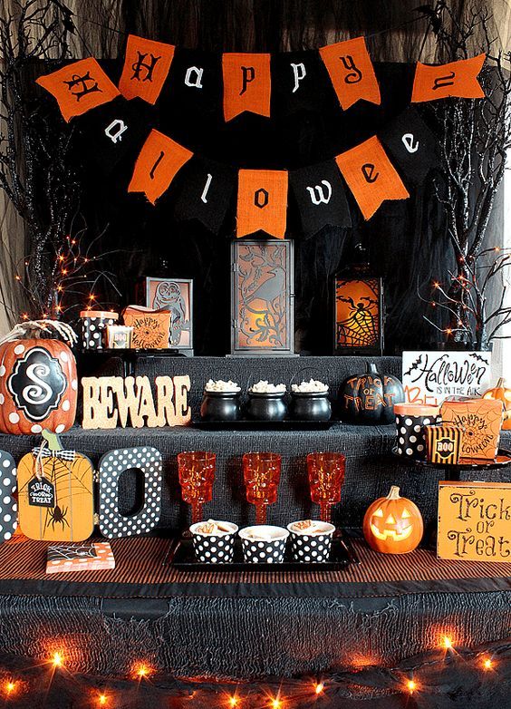 a bold food station for Halloween decorated with lights, bunting, letters, signs and colored glasses and cauldrons