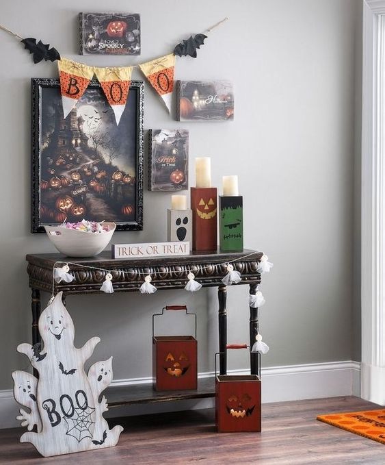 a chic Halloween entryway with a whimsy gallery wall, tassel garlands, ghosts, Jack-o-lanterns, a fabric bunting